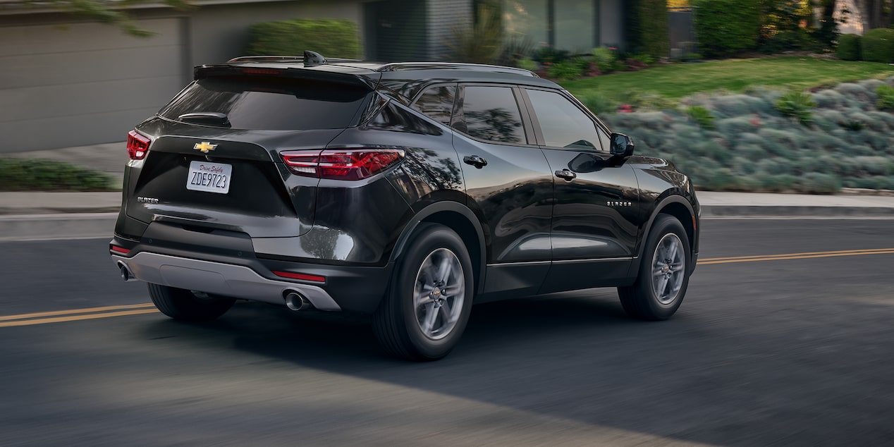 Rear Side View of a 2024 Chevrolet Blazer Driving Through a Neighborhood