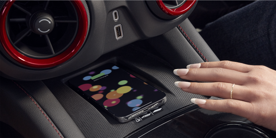 A Woman Reaching For Her Smartphone On The Wireless Charging Station