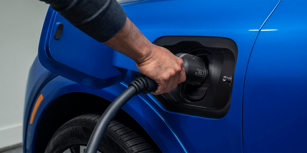 a person plugging in a blue vehicle to charge