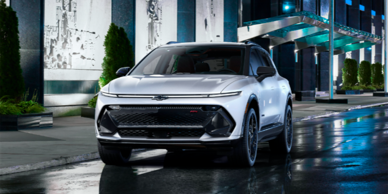 Toma de 3/4 del perfil delantero de la Chevy Equinox EV 2024 estacionada en una calle urbana por la noche