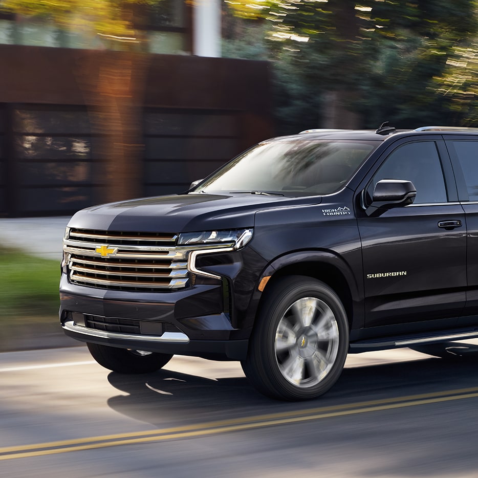 The Dark Ash Metallic MY24 Chevy Suburban Cruising Through a Residential Neighborhood