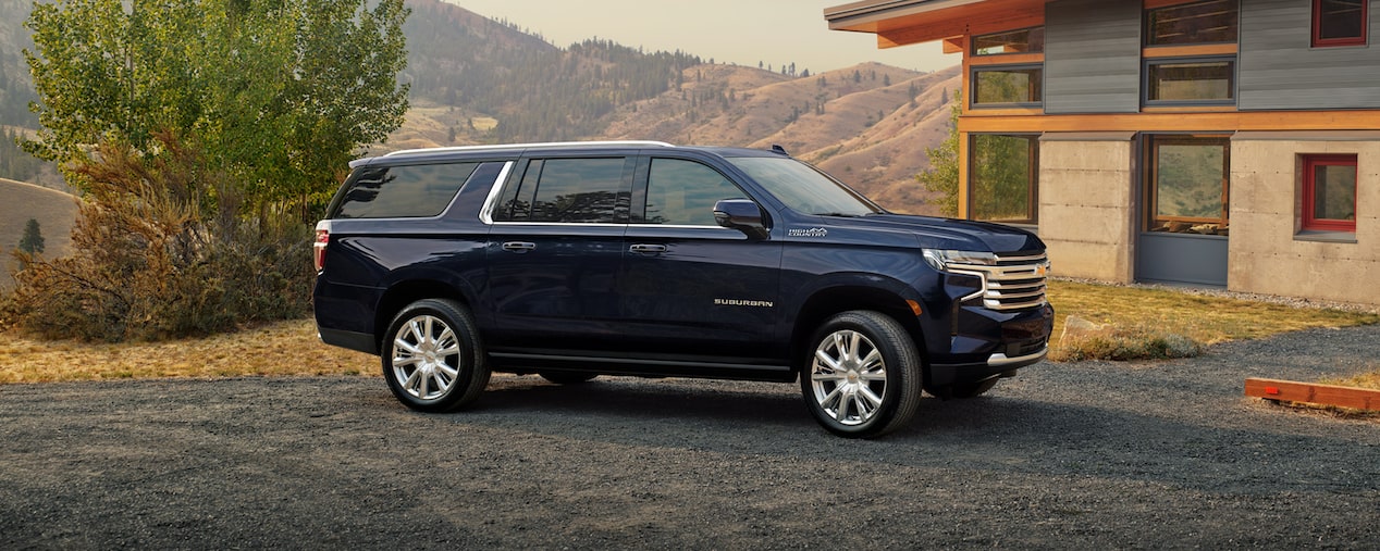 Una Chevy Suburban modelo 24 en Azul Medianoche Metálico estacionada en frente de una casa moderna