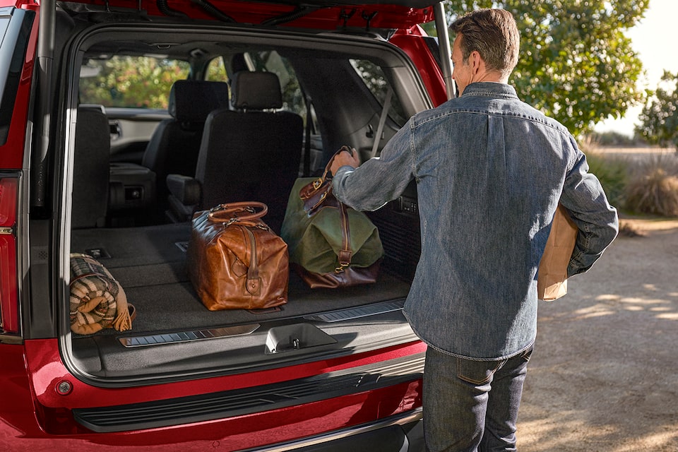 A Man Packing Camping Gear In The Trunk Of Her 2024 Chevy Tahoe