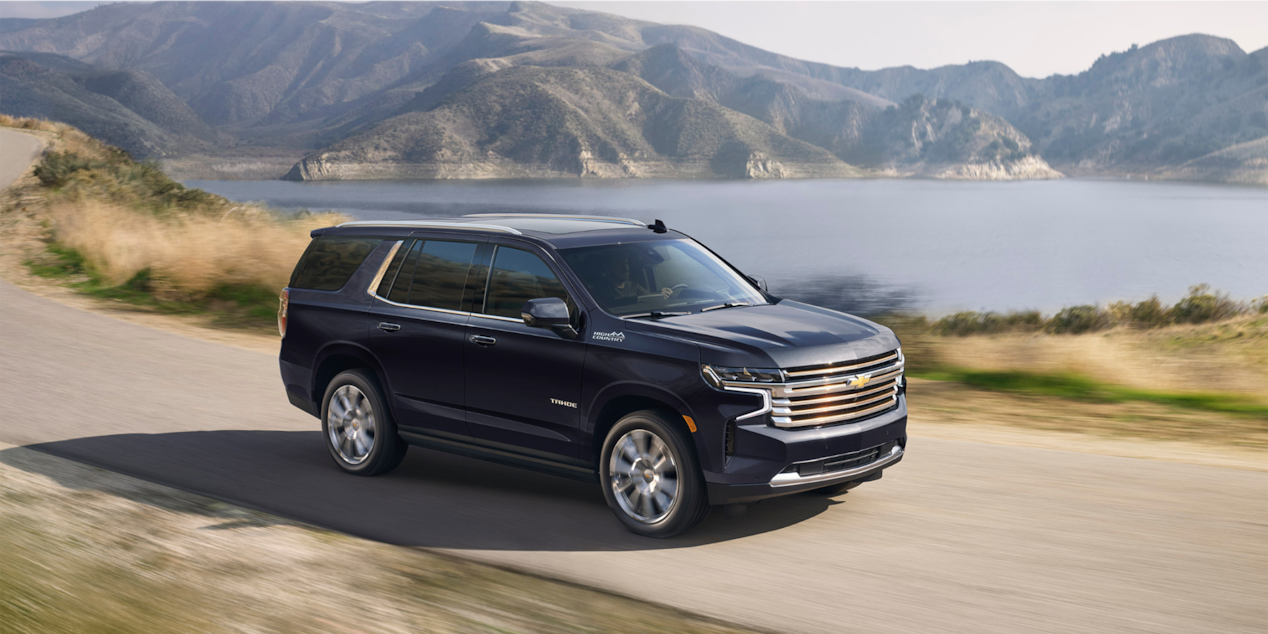 2024 Chevrolet Tahoe Full-Size SUV Exterior Side View Driving With A Scenic Lake In Background