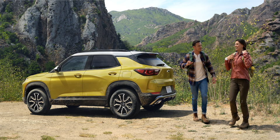 Dos personas hablando detrás de una Trailblazer 2024 en Amarillo Nitro Metálico estacionada