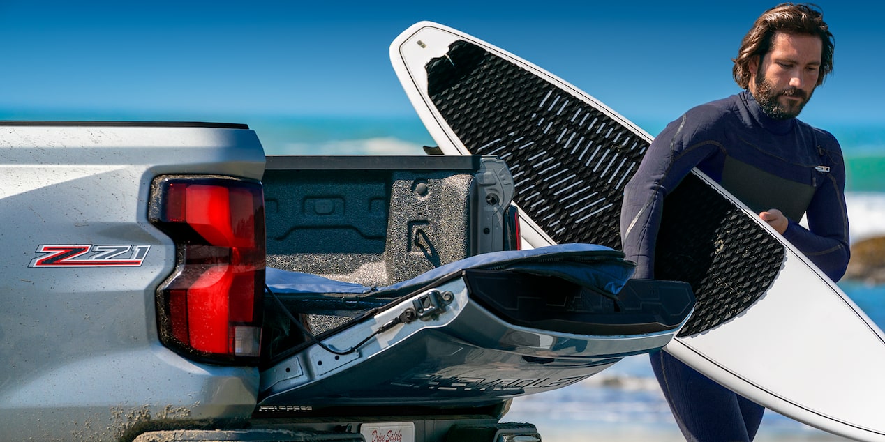 Un hombre con un traje de neopreno descarga su kayak de su Chevy Colorado