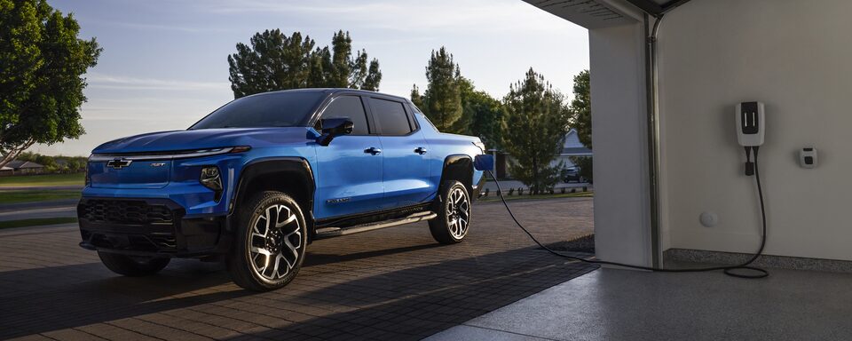 2024 Chevy Silverado EV Parked Outside A Garage Plugged Into a Charging Port