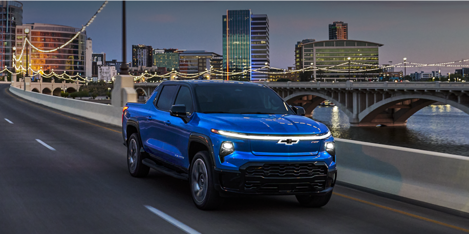 2024 Chevy Silverado EV Driving At Dusk On A City Bridge