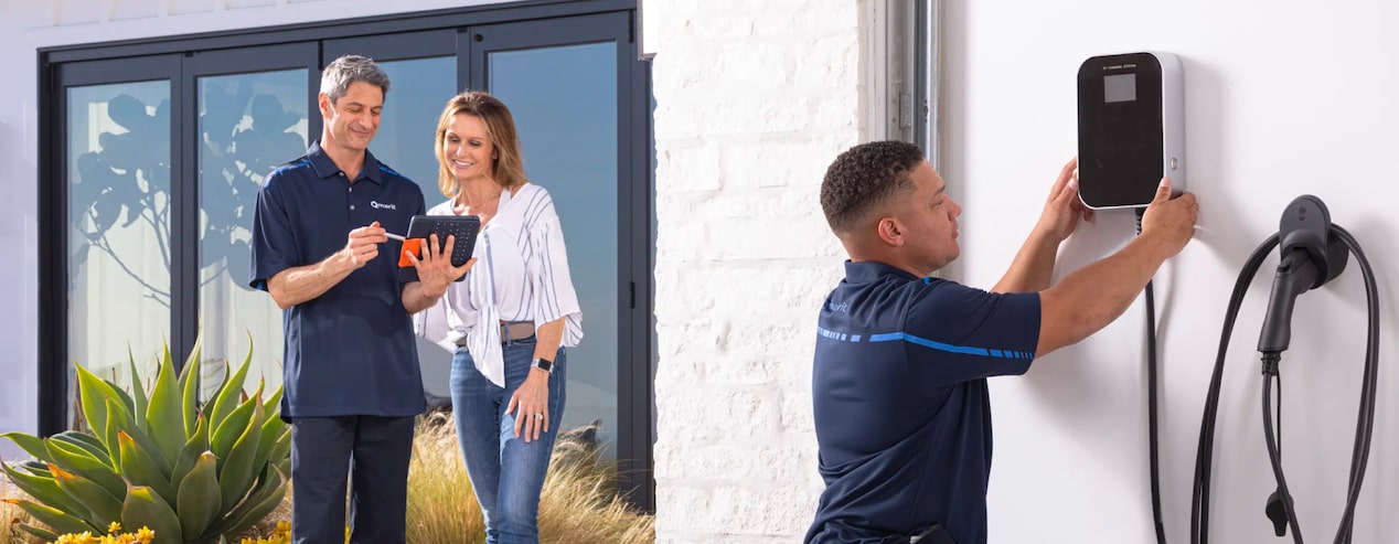 Technician Installing a Home Charging Station and a Second Technician Showing Home Owner How to Use it
