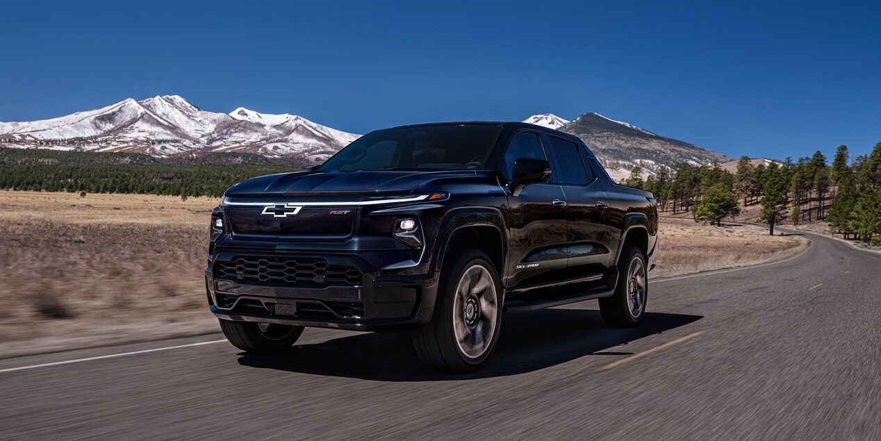Chevy Silverado EV Driving Down a Road with Mountains in the Background
