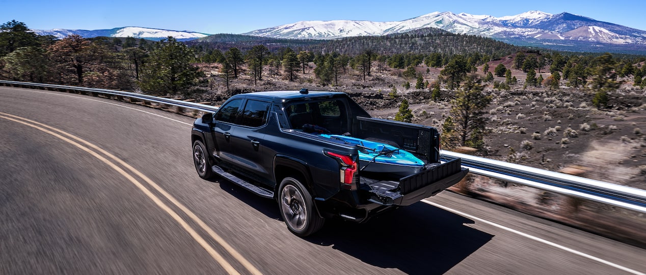 Chevy Silverado EV Driving Down a Road with a Kayake in the Truck Bed