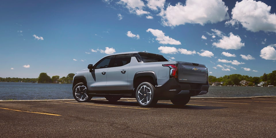 Toma de medio perfil trasera del lado del conductor de una Silverado EV LT estacionada cerca del agua
