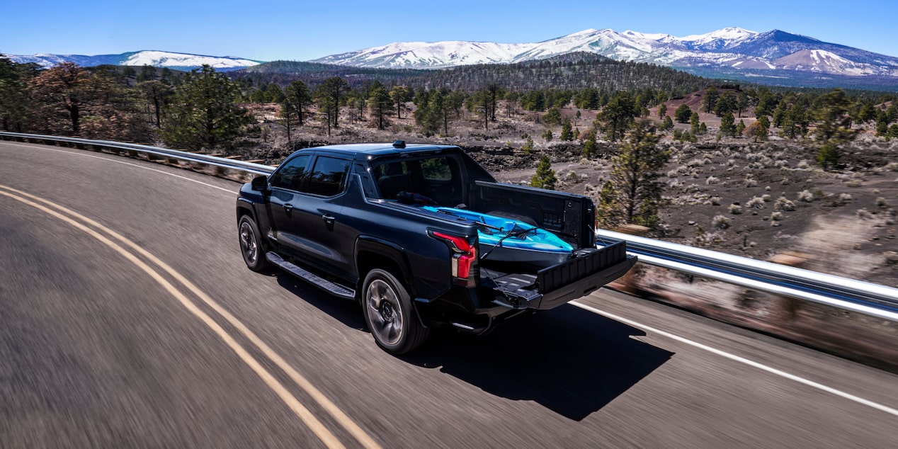Una Chevy Silverado EV 2024 circulando por una carretera con un kayak en la caja