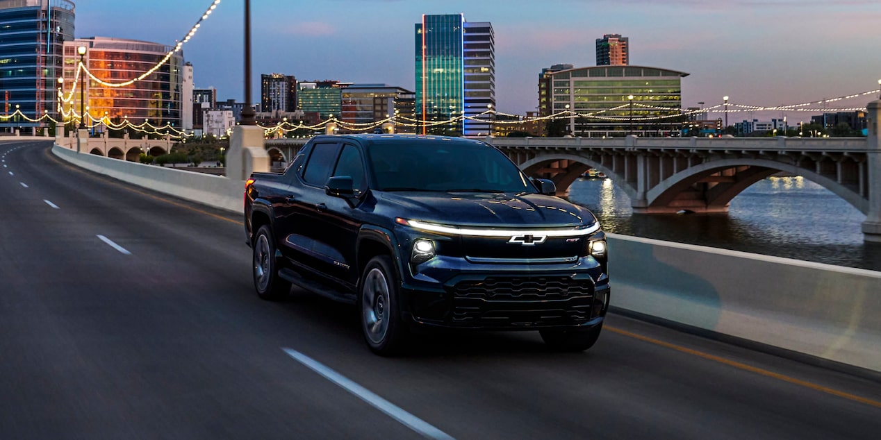 Una Chevy Silverado EV 2024 circulando al atardecer por un puente de ciudad