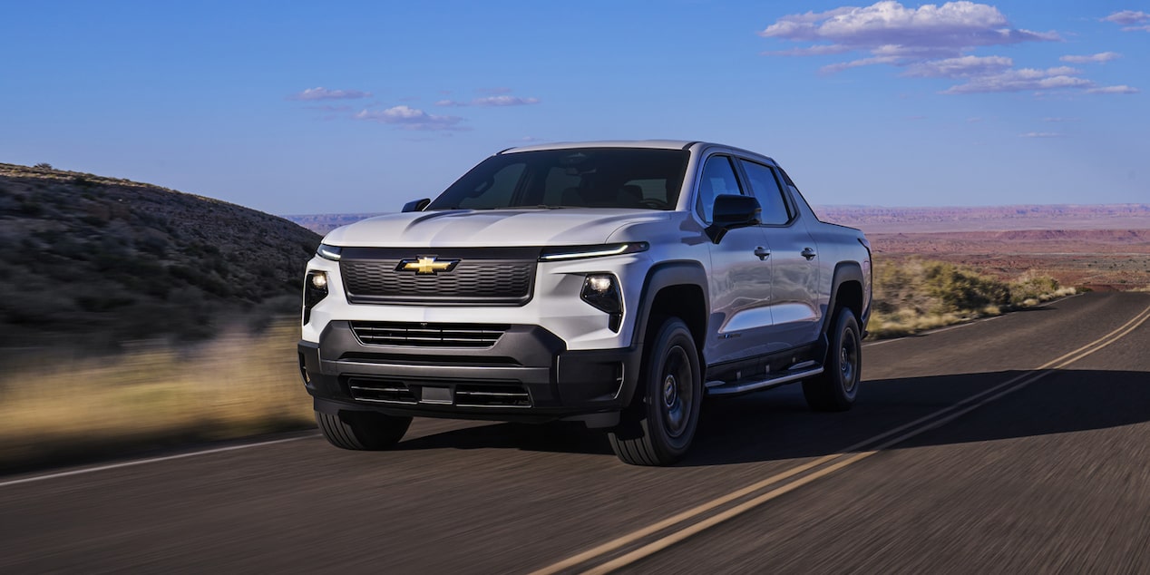 Camioneta de trabajo Chevy Silverado EV 2024 circulando por un camino con paisajes naturales