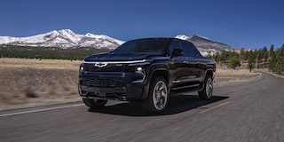 2024 Chevy Silverado EV Driving Down A Road With  Mountains In The Background