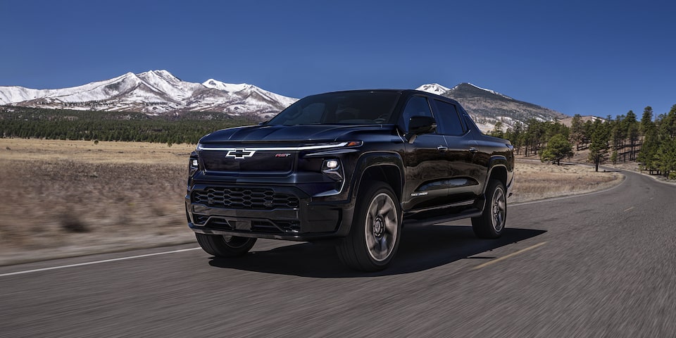 2024 Chevy Silverado EV Driving Down A Road With  Mountains In The Background