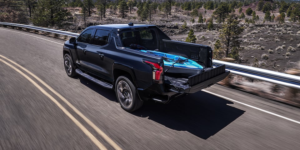 2024 Chevy Silverado EV Driving Down a Highway With A Kayak In The Bed