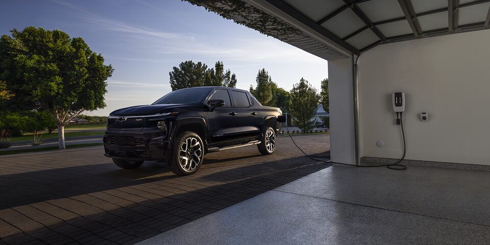 2024 Chevy Silverado EV Parked Outside A Garage Plugged Into a Charging Port