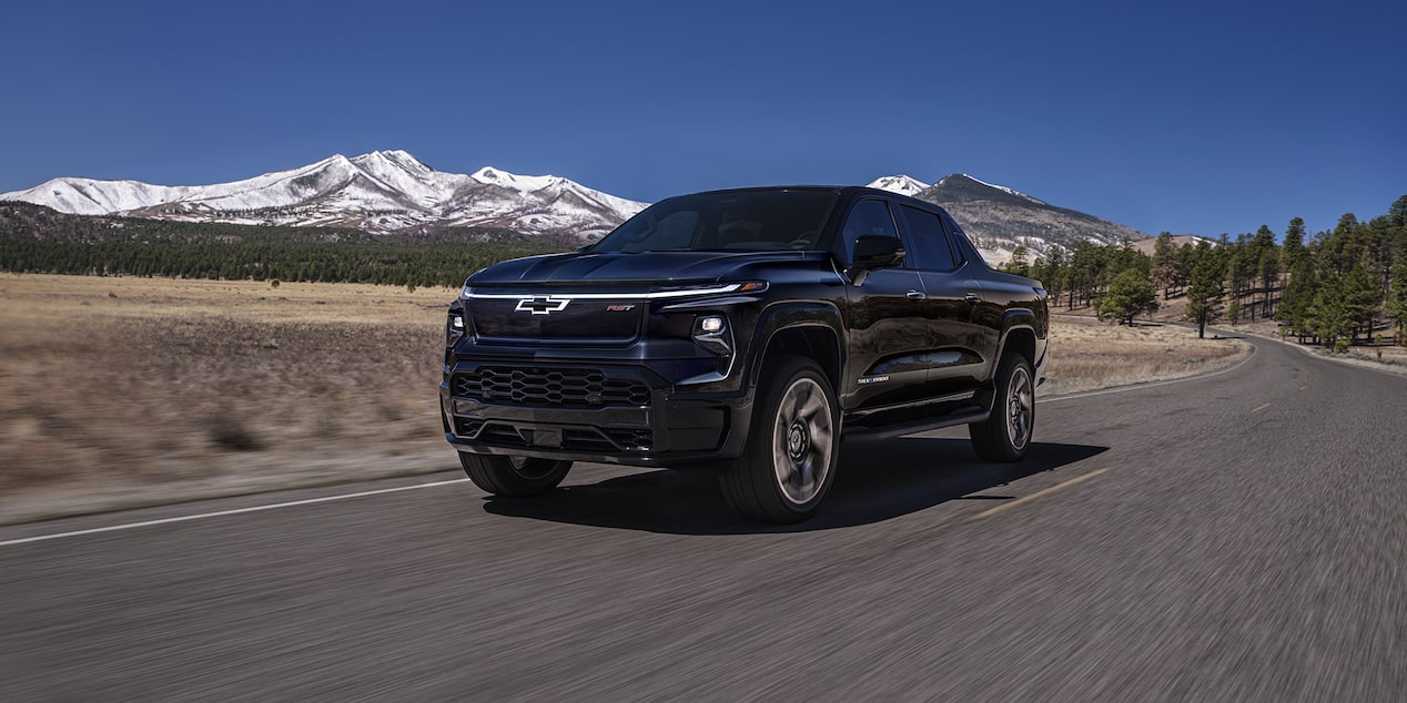 Una Chevy Silverado EV 2024 circulando por un camino con montañas de fondo