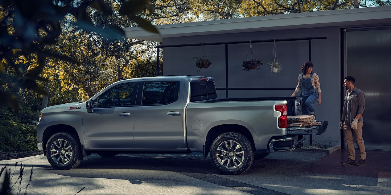 Family loading large wooden pallets into a Sterling Gray Metallic 2024 Chevy Silverado Crew Cab short bed LT Z71
