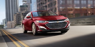 Vista frontal desde abajo de una Chevy Malibu color Rojo circulando por la ciudad