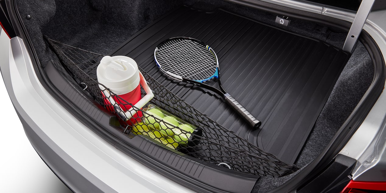 Vista aérea de la cajuela expuesta de una Chevy Malibu 2025 con una raqueta de tenis, pelotas y un termo