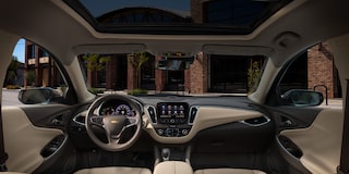 Vista interior frontal y central de una Chevy Malibu 2025 mostrando el panel con pantalla y el volante