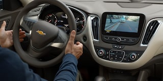 Un conductor estaciona una Chevy Malibu 2025 mirando el panel con pantalla