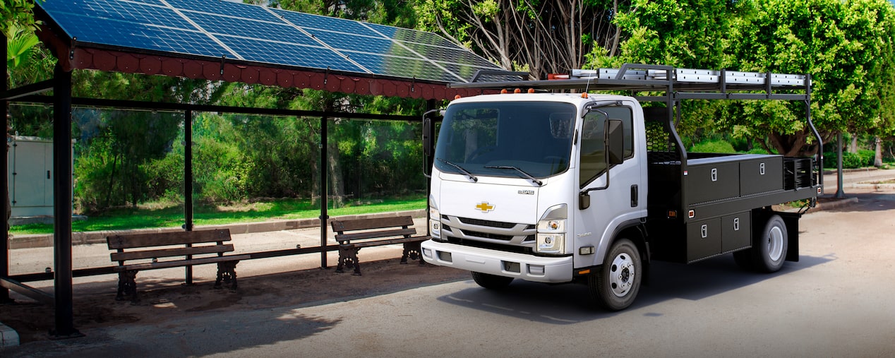Un camión Chevy de cabina adelantada baja 2025 estacionado cerca de una parada de autobús con techo de paneles solares