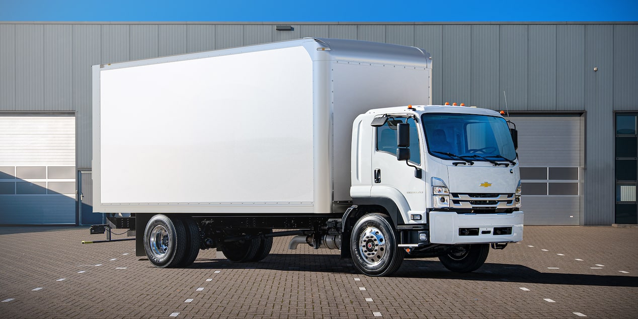 Un camión Chevy de cabina adelantada baja 2025 estacionado cerca de un almacén