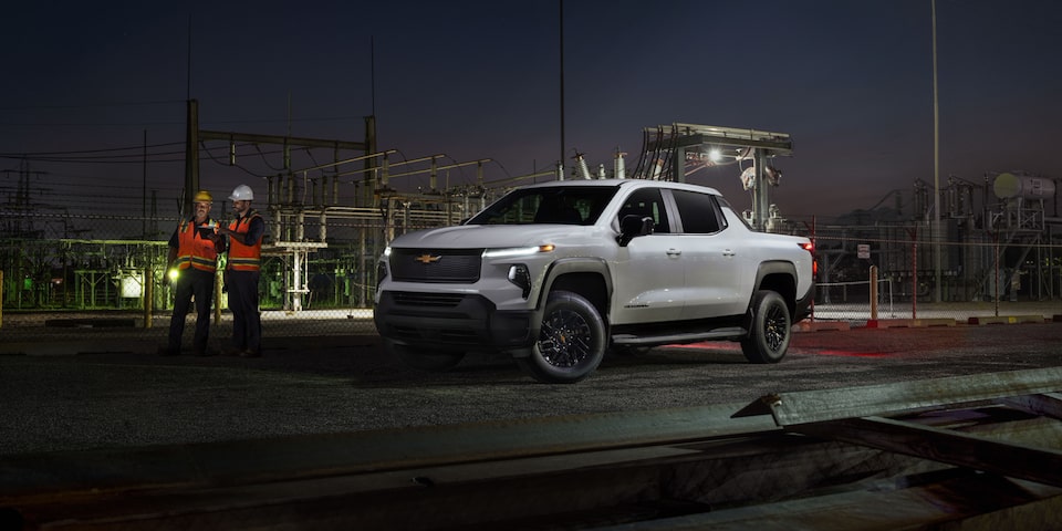 Vista de medio perfil de una Chevy Silverado EV 2025 estacionada en un camino de noche