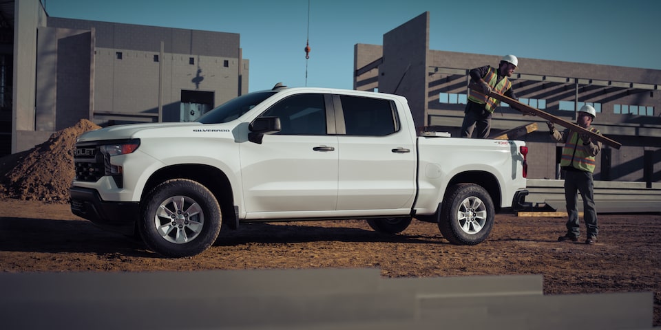 Dos obreros de la construcción descargando materiales de una camioneta Chevrolet Silverado 2025
