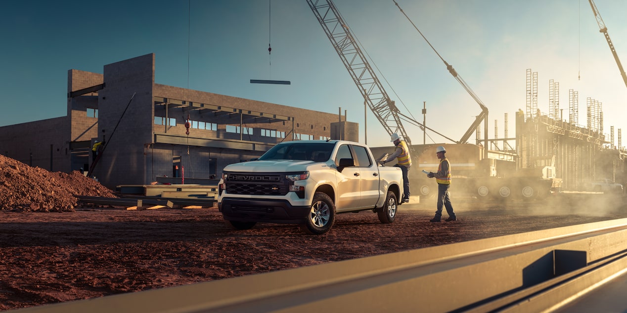 Dos trabajadores de la construcción de pie cerca de una camioneta Chevrolet Silverado 2024