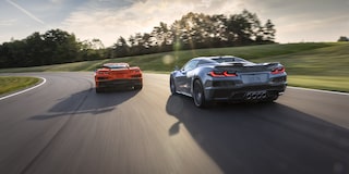 Two Orange and Silver Colored Chevy Corvette Z06s Racing Down the Road on a Sunny Day