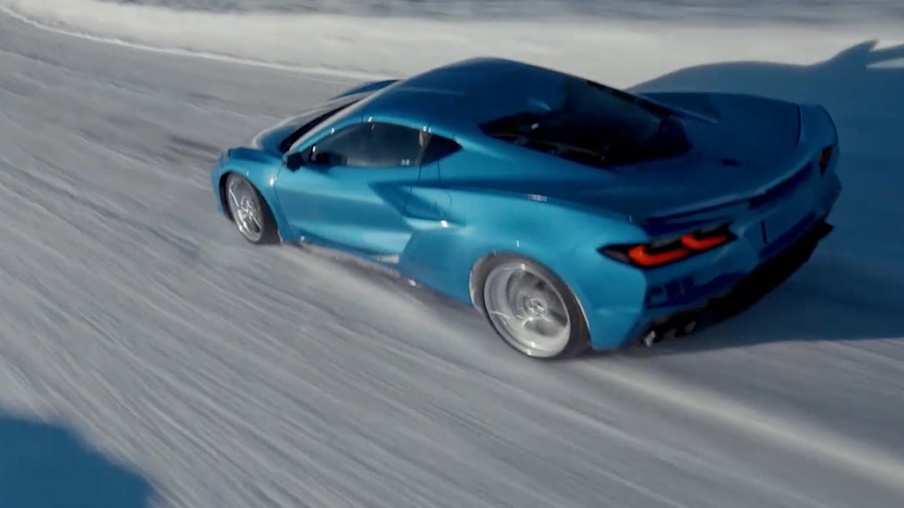 Vista frontal a la altura de los ojos de un Chevy Corvette E-Ray en Azul circulando por un camino rodeado de nieve