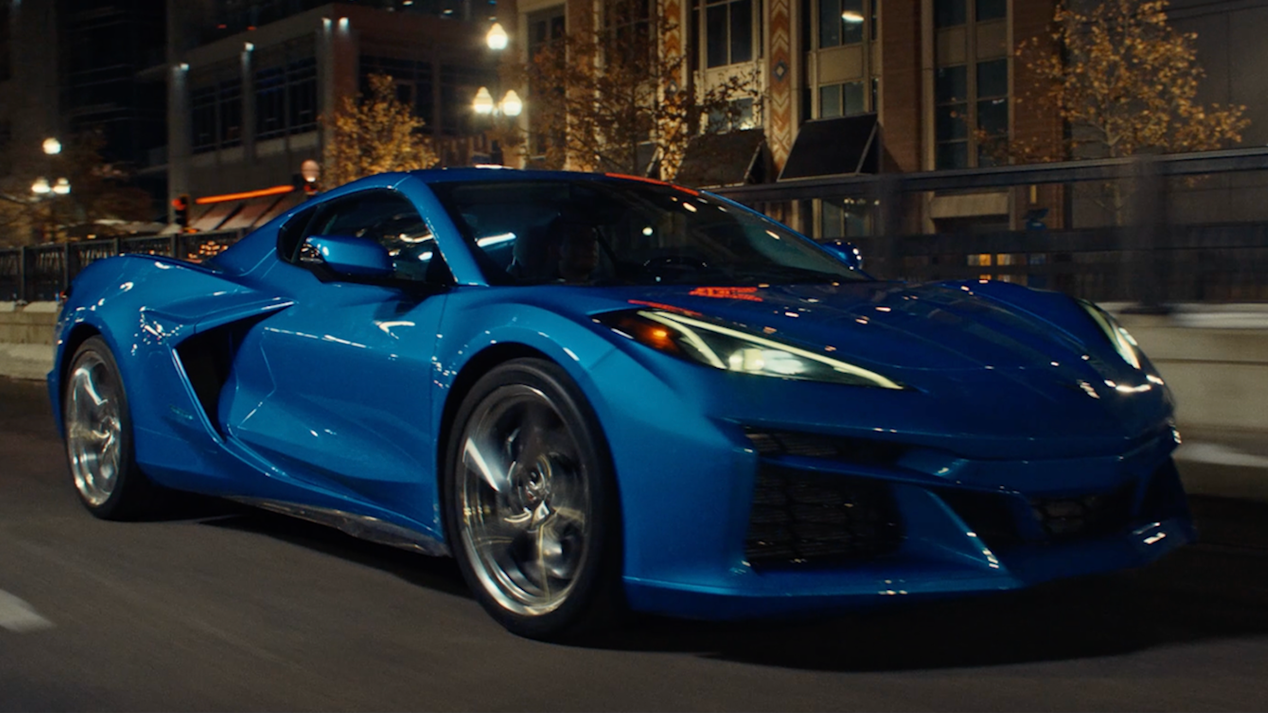 Vista de medio perfil de un Chevy Corvette E-Ray en Azul circulando por un camino, por la noche