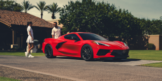 Three Quarters View of a Red 2025 Chevy Corvette Stingray with a Man and a Woman behind It