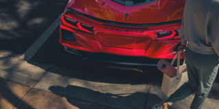 A Man with a Shopping Bag Walking Away from the Rear of a 2025 Red Chevy Corvette Stingray