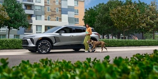 Side View of a Gray 2025 Chevy Blazer EV with a Woman and a Dog Next to It