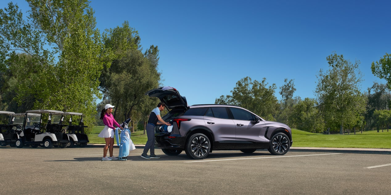 A Man Putting Something in the Trunk of Chevy Blazer EV with a Woman Next to Him