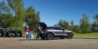 A Man Putting Something in the Trunk of Chevy Blazer EV with a Woman Next to Him