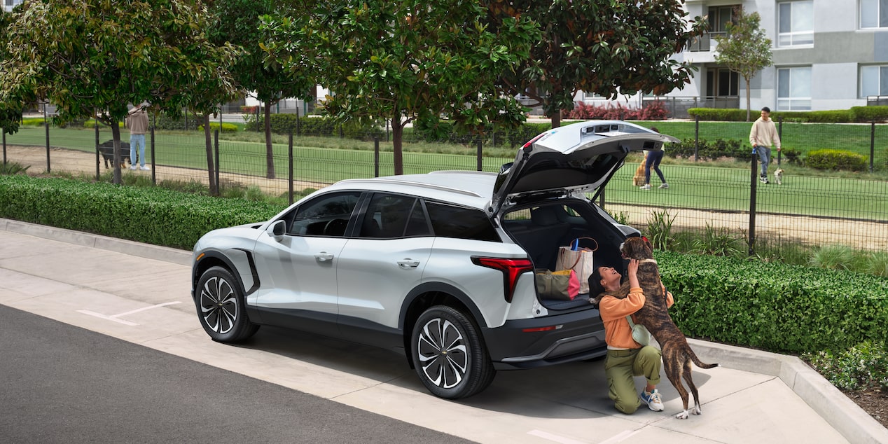 A Woman Playing with Her Dog While the Trunk of Her Chevy Blazer EV Trunk Is Open