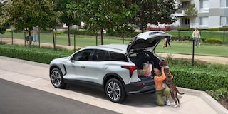 A Woman Playing with Her Dog While the Trunk of Her Chevy Blazer EV Trunk Is Open