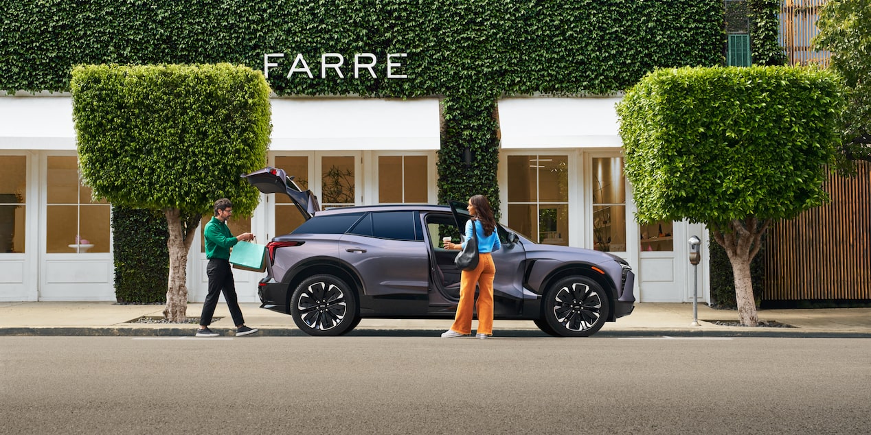 A Woman Is Seen Holding the Front Door and a Man Has Opened the Trunk of the 2025 Chevy Blazer EV
