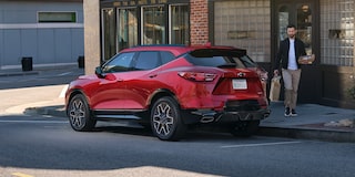 Man Walking Toward His 2025 Red Chevy Blazer Parked at a Shop
