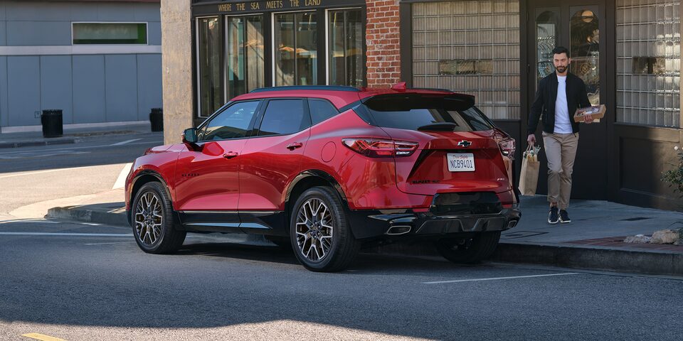 Man Walking Toward His 2025 Red Chevy Blazer Parked at a Sho
