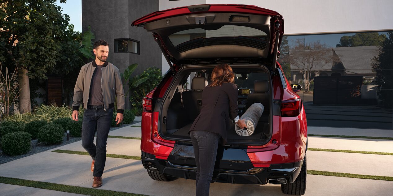 A Woman Putting a Mat Inside the Trunk of a 2025 Red Chevy Blazer