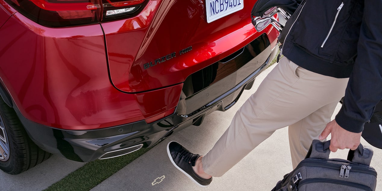 A Man Using His Leg to Alarm the Sensor of a Red 2025 Chevy Blazer to Open Its Trunk