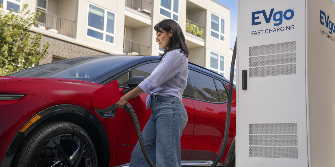 Low Angle View of a Woman Charging a Red 2025 Chevy Equinox EV